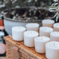 The One Co Cheshire Candle Refills displayed on a picnic basket outdoors